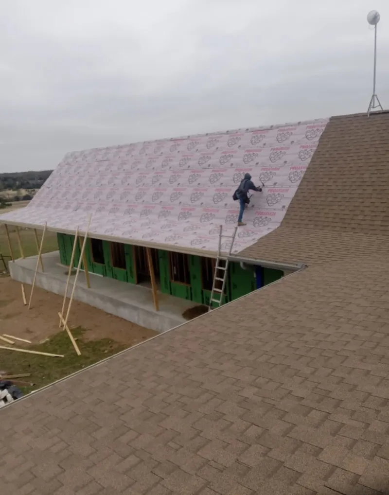 Worker preparing underlayment for a metal roof installation in Powell